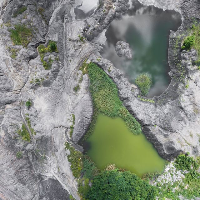 A mesmerizing aerial view capturing a unique natural rock formation with contrasting green waters. Useful for nature blogs, geological studies, environmental projects, and travel magazines. Great for emphasizing the beauty and complexity of natural terrains and water bodies.