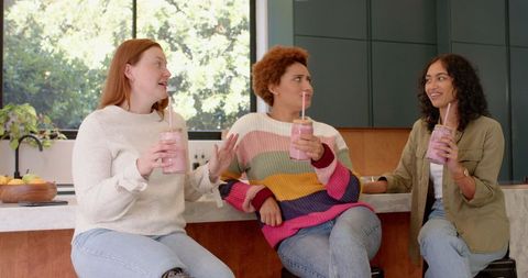 Diverse Women Enjoying Smoothies in Modern Kitchen Setting