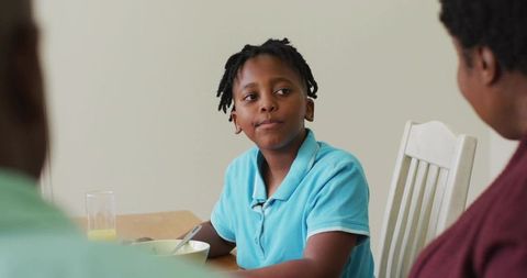 Family breakfast moment with boy eating cereal in home setting