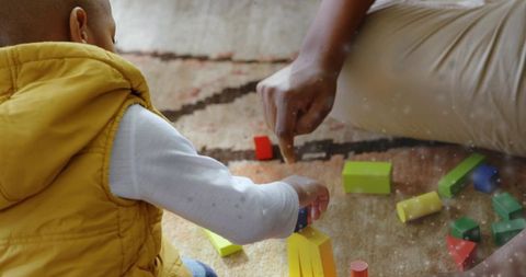 Young child stacking colorful wooden blocks with caregiver on patterned rug, sunlit playtime