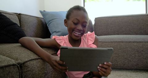 Smiling African American Girl Using Tablet on Living Room Floor for Learning and Play