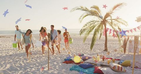 Diverse Friends Enjoying Picnic at Beach with Patriotic Decorations