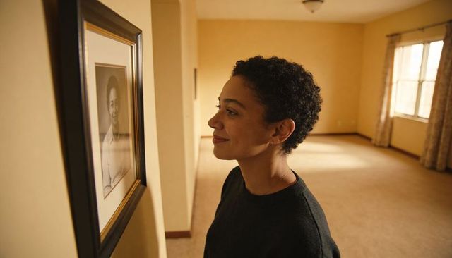 Woman reflecting while viewing framed portrait in minimalist empty living room interior
