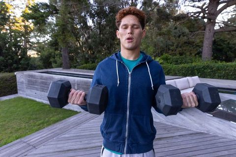 Fit Man Lifting Dumbbells on Backyard Deck for Outdoor Workout