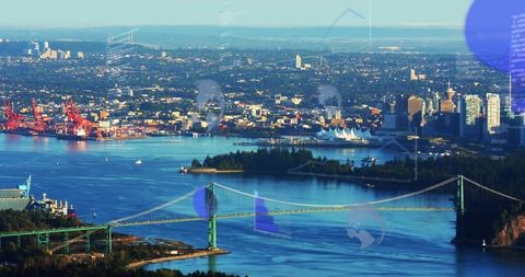 Green lions gate bridge crossing vancouver harbor with skyline, port cranes and waterfront