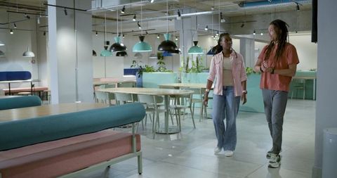 African american colleagues walking and talking in modern office lounge with pastel design