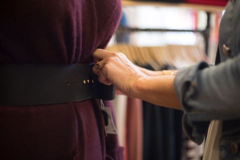 Close-up of hand adjusting belt on mannequin display