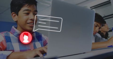 Teen typing on laptop in classroom with chat bubble icon representing online collaboration