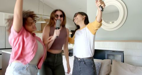 Diverse Female Friends Singing and Dancing in Living Room Celebration