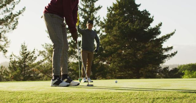 Two men enjoying a game of golf on a clear sunny day. Ideal for promoting outdoor activities, golfing resorts, sports gear, and advertisements related to recreation and leisure.