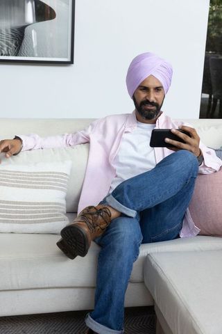Indian Man Relaxing with Smartphone in Modern Living Room