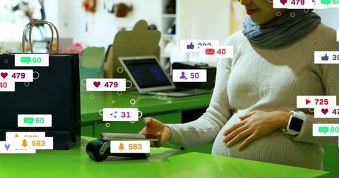 Pregnant woman tapping contactless card at boutique counter with social media notifications