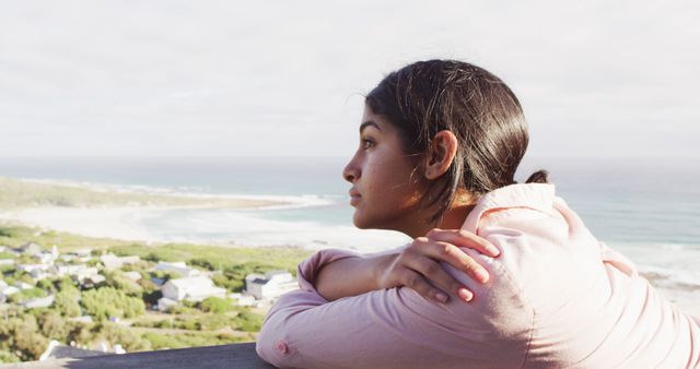 Image of thoughtful biracial woman by sea looking into distance. Relax, leisure and vacations concept.