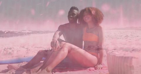 Smiling couple relaxing on sunlit beach towel with surfboard and striped beach bag