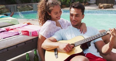 Happy Couple Embracing by Poolside with Guitar