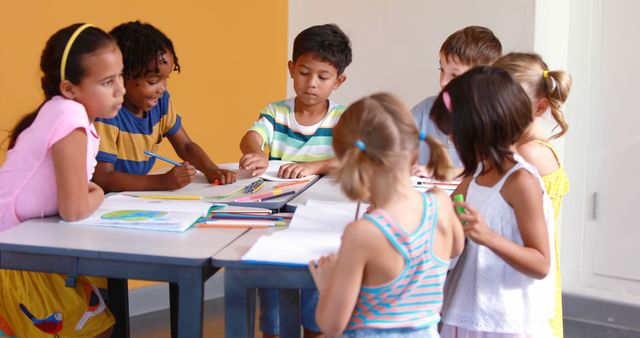 Children are gathered around desks engaged in collaborative learning activities. The scene is vibrant, with students participating in drawing and other educational tasks. Perfect for illustrating concepts of elementary education, teamwork, diversity in schools, creative classroom settings, and early childhood learning.