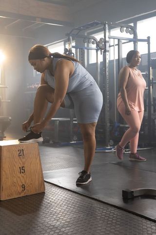African american women tying shoes on plyo box preparing strength training session
