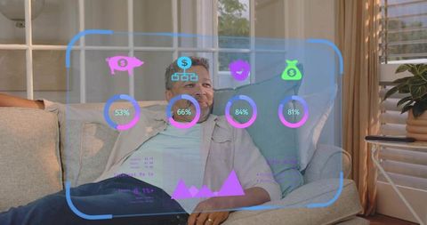 Mature man relaxing on sofa viewing augmented reality finance dashboard with holographic icons