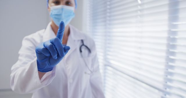 Caucasian female doctor wearing face mask and surgical gloves touching screen - Download Free Stock Photos Pikwizard.com