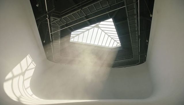 Skylight casting sunbeams into curved atrium with industrial catwalks