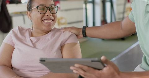 Smiling Woman Receiving Personalized Fitness Coaching and Support with Tablet Consultation at Gym