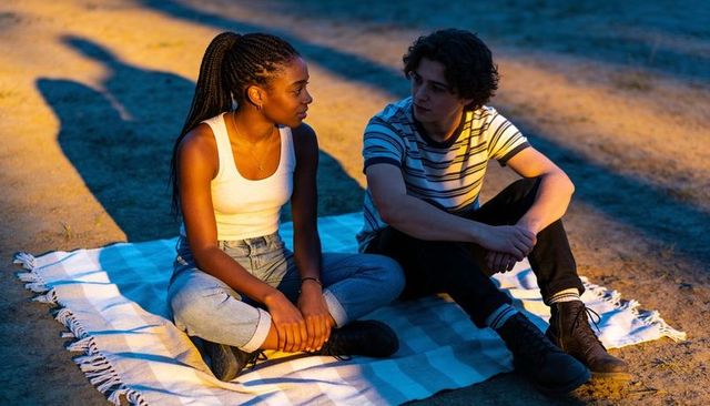 Young couple sitting on blanket at sunset sharing intimate conversation and quiet bond