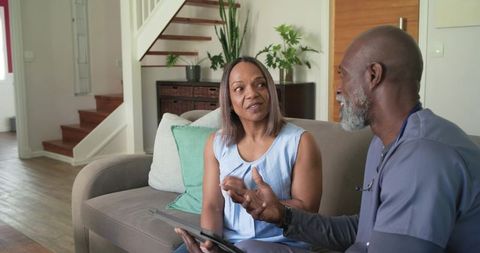 Home care consultation with nurse using tablet in living room with natural light