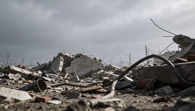Urban demolition rubble showing collapsed concrete slab, exposed rebar and tangled cable