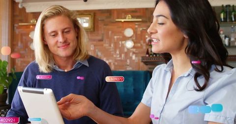 Professionals Analyzing Data on Tablet in Contemporary Cafe Setting