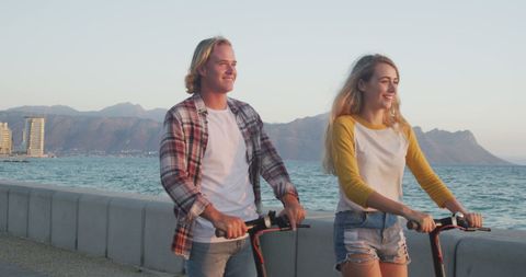 Couple Riding Scooters by the Beach at Sunset Highlighting Romance and Adventure