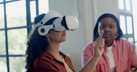 African American Women Collaborating with White VR Headset in Bright Sunlit Workspace