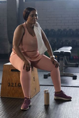 African american woman sitting on plyo box resting after workout in industrial gym