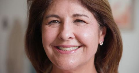 Confident middle-aged woman smiling indoors in natural light