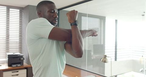 Man stretching arms in modern home office for wellness break
