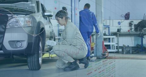 Crouching mechanic loosening lug nuts on suv with data overlay