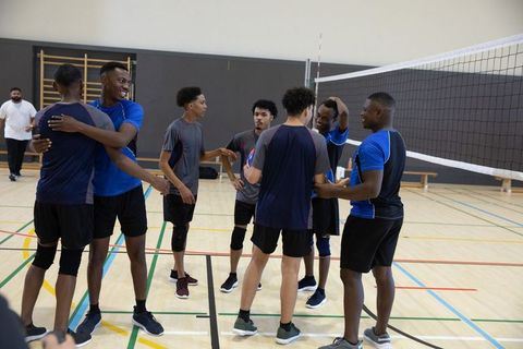 African american male volleyball team celebrating point on indoor court showing teamwork