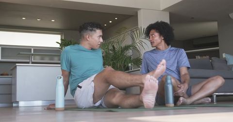 Couple stretching on yoga mats after workout in bright open-plan living room