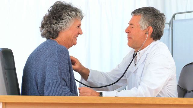 Elderly patient in a clinical setting receiving a heart checkup. Suitable for healthcare articles, brochures about patient care, and educational materials on ensuring senior health. Demonstrates professional care and reassurance in medical examinations.