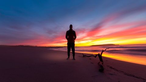 Person Standing on Beach at Vibrant Sunset