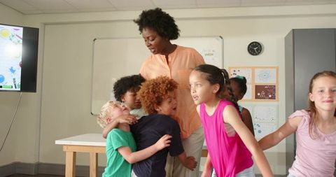 African American Teacher Guiding Diverse Elementary Children During Classroom Activity