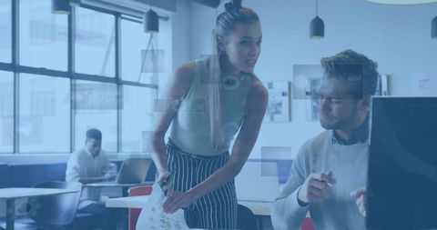 Female colleague presenting color charts to coworker in modern open-plan office workspace