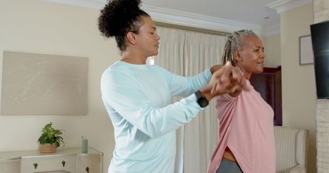 Trainer Assisting Senior Woman with Stretching at Home