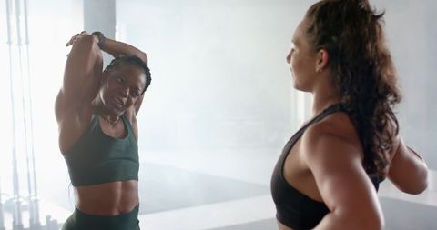 Women Stretching and Interacting in Modern Gym Environment