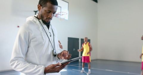 Coach Analyzing Game Data on Tablet in Basketball Gym Facility