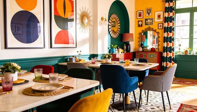 Eclectic colorful dining room featuring velvet chairs, marble tables, geometric art