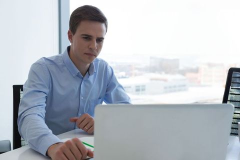 Focused Young Professional Working on Laptop in Modern Office Setup