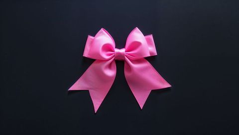 Pink silk bow on black surface expressing elegance and contrast