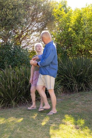 Senior couple enjoying sunny garden stroll man gently holding partner's arm