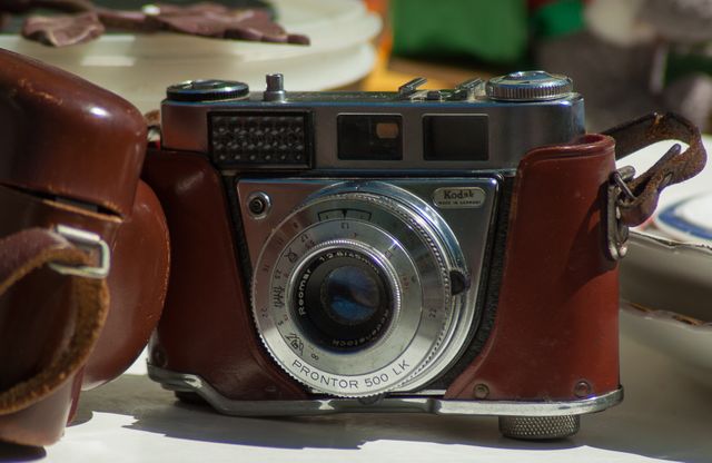 This vintage Kodak camera with a leather carrying case is perfect for illustrating retro photography themes, analog experiences, or historical articles on unique technological advancements in photography. It is also suitable for vintage collection promotions, antique shop advertisements, or any creative projects needing an old-fashioned touch.