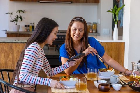 Mother and Daughter Bonding Over Meal and Smartphone at Home